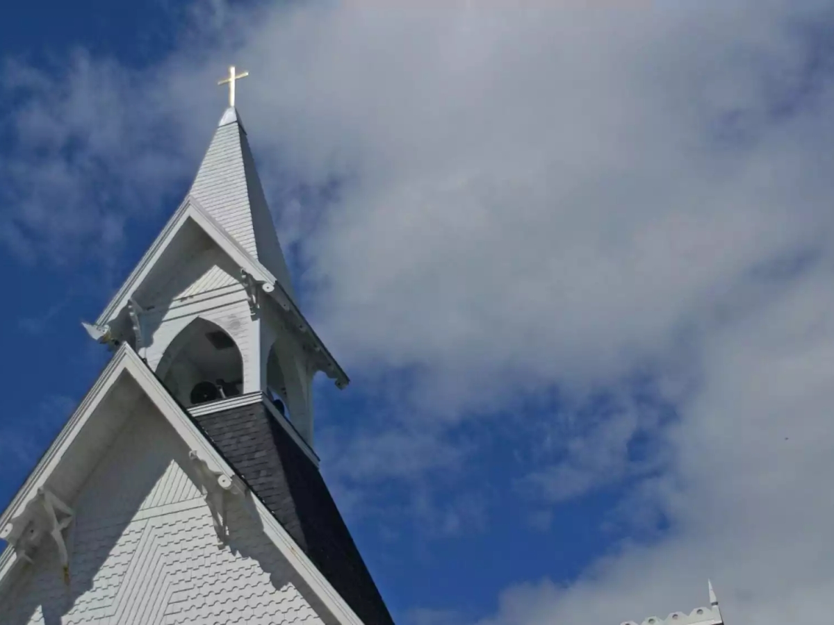Picture of white church tower against the sky and clouds