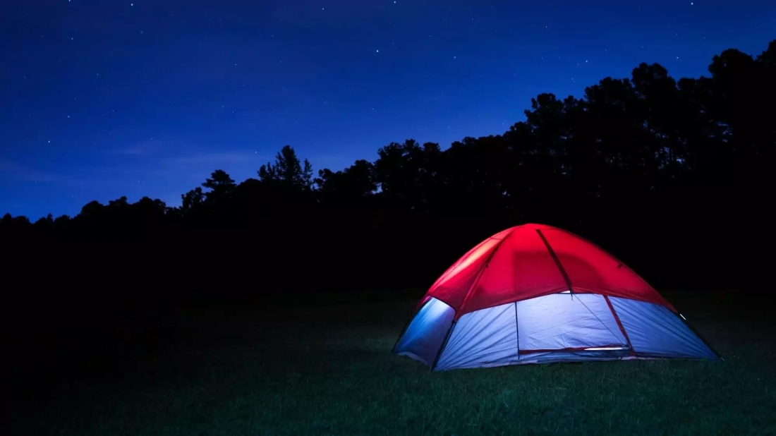 Picture of red and blue tent with lights on against a dark background